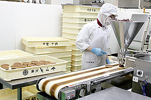 The Filling Depositor (option) deposits the coarse red bean paste, and it is sandwiched by hand.