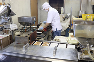 Torayaki in production by a Compact Type Dorayaki Machines. Two machines are laid out in an L shape with one operator working with both.