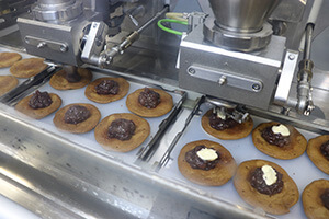 The baked pancakes are lined up on the sheet pan and red bean paste and butter is deposited.