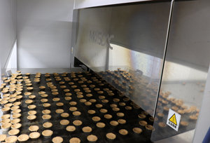 Exit of the Tunnel Oven. Batter is deposited in mold tops one by one and baked.