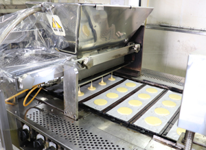 Torayaki in production. A piece of paper is laid on a copper sheet, and batter is deposited.