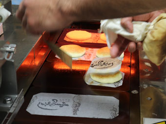 The baked pancakes are put together and removed from the machine with the paper attached.