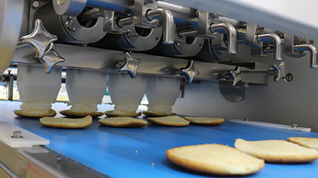 At the edge of the conveyor belt, guides are in place to line up the pastry shells at certain points.