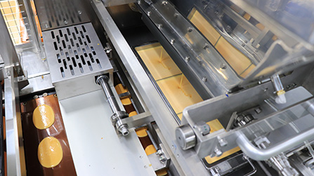 生地ホッパーの下にはスライド口金タンクがあり、銅板の上をスライドしながら楕円形状に絞っている